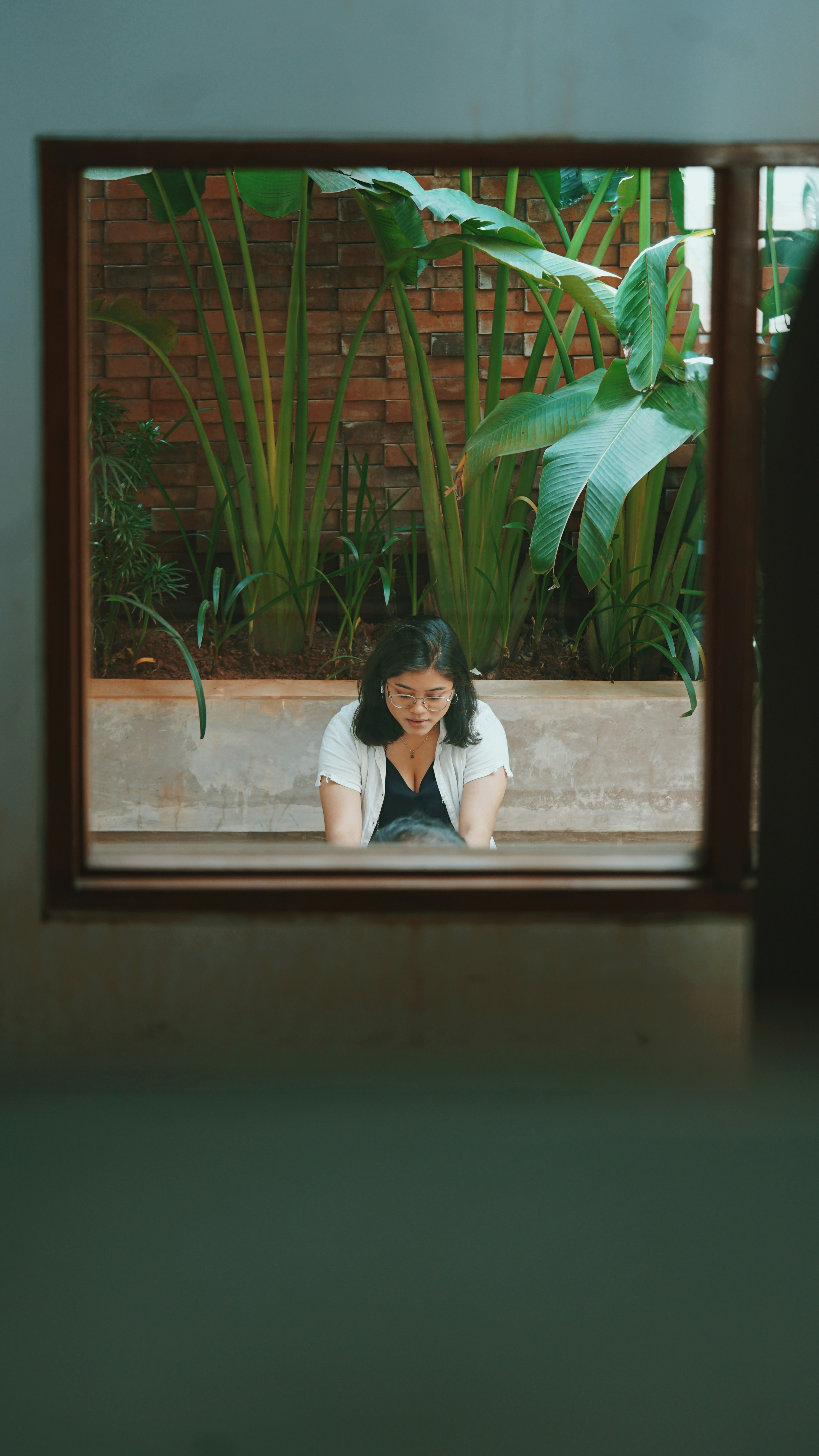 woman in white shirt sitting on window